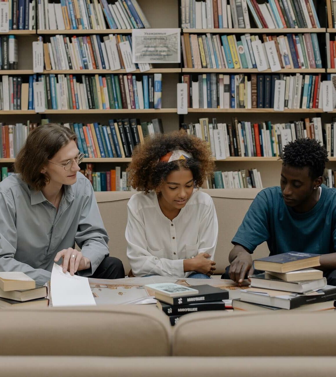 3 people sitting in a library and reading together