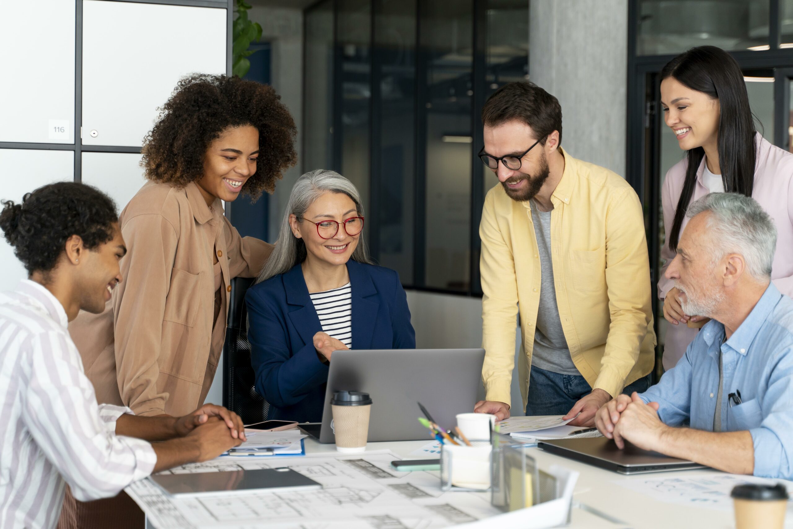 Group of people gathered around a table smiling and looking at a computer screen